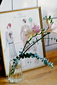 Nahaufnahme einer Glasvase mit Blumen vor einer gerahmten Zeichnung