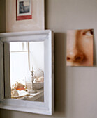 Spiegelung von Dekoobjekten auf der Fensterbank in einem Spiegel aus weißem Holz
