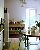 A modern kitchen with dining area wooden floor round table retro chairs side unit open door place settings