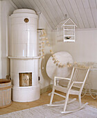 White wood rocking chair next to traditionally Scandinavian tiled wood burning stove