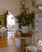 Detail of a decorated potted Christmas tree on a stone table surrounded by presents