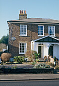 Exterior of a traditional Georgian townhouse with a front garden and a large white porch