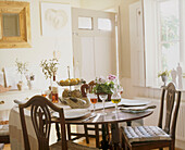 A traditional dining room with wooden table with place settings and a bowl of fruit accompanied by two upholstered chairs