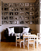 Sofa and small set of table and chairs below a lot of framed photographs