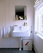A detail of a country style bathroom white sink and a mirror above it