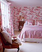 Doppelbett in einem rosa Schlafzimmer mit Toile de Jouy-Tapete und passenden Vorhängen