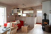 Stove with lit fire in the corner of open plan country style kitchen with dining table and chairs