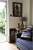 Lamp on wooden table next to blue sofa with cushions