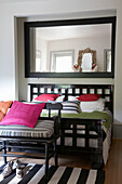 Mirror above contemporary double bed with pink cushions