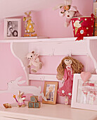 A detail of a child's pink bedroom painted shelves doll figures soft toys