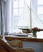 Korbstuhl vor einer Fensterbank mit Modellboot