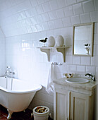 Washbasin set in cupboard unit with marble top next to freestanding roll top bathtub