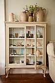 Seashells and ceramic jugs in glass fronted cabinet in Port Issac beach house Cornwall