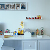 Weißer Kinderschreibtisch mit Spielzeug in einem weiß gestrichenen Zimmer
