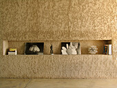 Detail of textured concrete wall with recessed shelf with pictures books and magazines