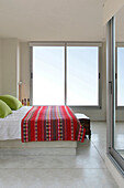 Bed with embroidered throw and lime green cushions with sliding doors