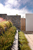 Grey granite stone walls and steps with Gramineae grasses in garden designed by Alejandra de Domenicci