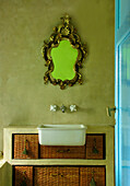 Spiegel mit vergoldetem Rahmen über Waschtisch mit Rattankörben