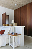 White painted bed with freestanding headboard and wooden fitted wardrobes