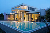 Contemporary glass cube house with swimming-pool merging exterior to bedrooms and living-room