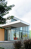Fassade eines Glaskubus-Hauses mit ausladendem Portikus