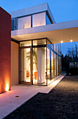 Fassade eines Glaskubus-Hauses im brutalistisch-minimalistischen Stil mit Farbflächen und erweitertem Portikus