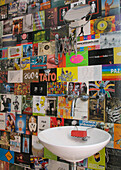 Badezimmerwände mit verschiedenen Postkarten und rundem Waschbecken ausgekleidet