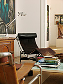 Black reclining chair with sideboard and books on coffee table