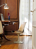 View through open door to study with chair at desk and desk lamp