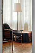Metallgerahmter Stuhl am Tagesbett in einem Zimmer mit Vorhängen