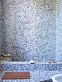 Grau gefliester Duschbereich mit hölzernem Entenbrett
