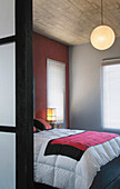Blick in ein Schlafzimmer mit silbernen und roten Wänden und einer Holzdecke