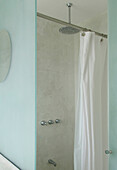 Shower cubicle with metal shower head and white shower curtain