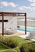 Essbereich und Swimmingpool mit Gartenmöbeln und Rasen mit Linienzeichnungen aus Lapacho-Holz