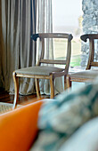 Carved wooden chairs at window with curtains