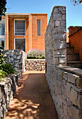 Beach house exterior viewed through pathway with stone wall