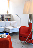 Matching red armchairs in tiled room with bookcase and corner sofa
