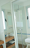 Badezimmerregal im Spiegel neben einer Duschkabine mit Glastür