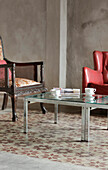 Living room with innovative mat on lime tiles chromium plated armchair and tables purchased at auction and wall of unpainted concrete plaster