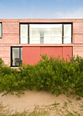 Rosa gestrichene Hausfassade mit Schiebeläden und Balkon