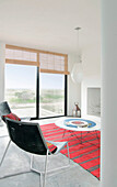 Metallgerüstete Stühle in weißem Strandhaus-Wohnzimmer mit gestreiftem rotem Teppich