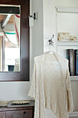 Lace cardigan hangs between bedroom mirror and shelves