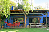 Blue painted veranda with natural wood awning and contrasting red hammock