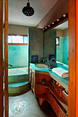 Aquamarinfarbenes Badezimmer mit Holzmöbeln und Regalen, Weidenkörben und Betontheke