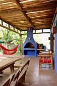 Oak table and bench seats with cactus at doorway to blue painted veranda