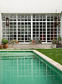 Großes weißes Fenster mit Blick auf den Swimmingpool in einem Garten mit Rasen