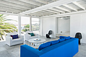 White living room with large windows vibrant blue sofa with sliding doors to bedroom