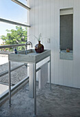 Wash stand in panelled bathroom with concrete flooring