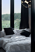 Unmade contrasting black and white bed at window with rural view