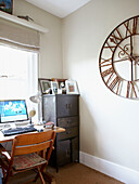Chair at window desk in study with brass clock